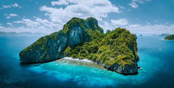 Aerial drone panorama picture of tropical paradise epic Entalula Island. Karst limestone rocky mountains surrounds the blue lagoon with beautiful coral reef Aerial drone panorama picture of tropical paradise epic Entalula Island. Karst limestone rocky mountains surrounds the blue lagoon with beautiful coral reef. el nido photos stock pictures, royalty-free photos & images