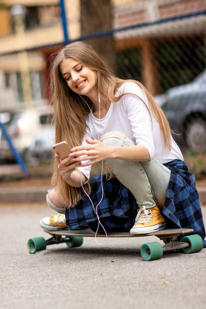 istock Female Skateboarder is Using a Mobile Phone in the Street 1157843761