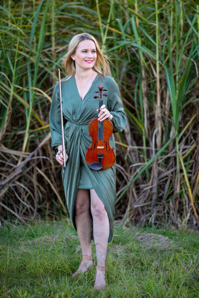 istock Beautiful Woman Playing Antique Violin In Cane Fields 1157845543