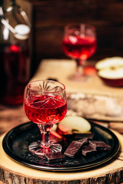 Glass of homemade redcurrant nalewka with apple slices and chocolate Glass of homemade redcurrant nalewka with apple slices and chocolate on metal plate nalewka stock pictures, royalty-free photos & images