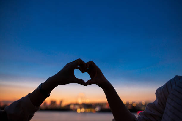 istock Young female friend making a hear shar with their hands at sunset 1157850922