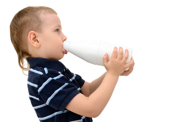 istock Child drinks milk from a bottle on a white background 1157852216