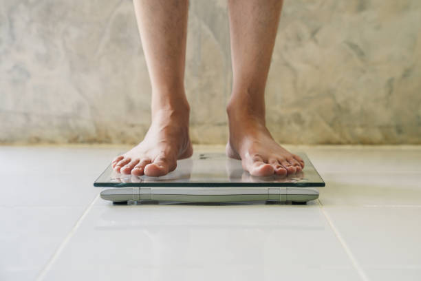 Male on weight scale on floor background, Diet concept. Male on weight scale on floor background, Diet concept. eating disorder stock pictures, royalty-free photos & images