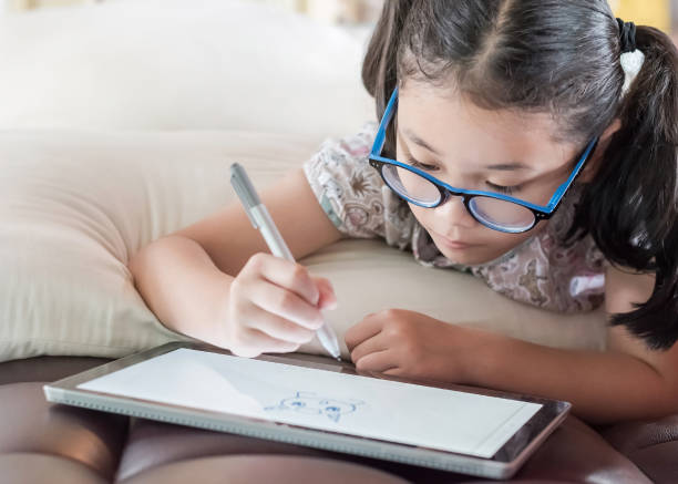 istock Asian school child girl using smart  tablet device digital technology drawing on innovative touchscreen surface 1157859867