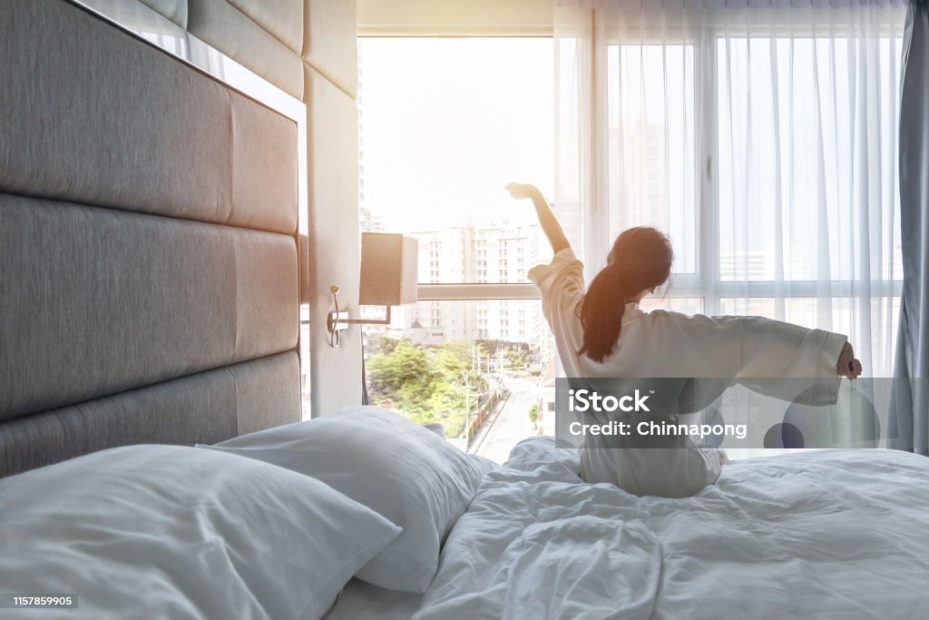 Hotel room comfort with good sleep easy relaxation lifestyle of Asian girl on bed have a nice day morning waking up, taking some rest, lazily relaxing in guest bedroom in city hotel Hotel Stock Photo