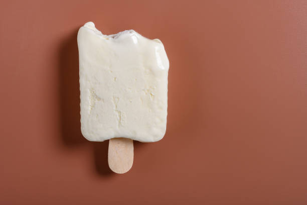 top view half eaten milkshake flavor popsicle on a brown background with copy space