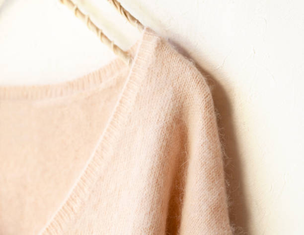 istock light pink sweater hanging on clothes hanger on white background. 1157880267