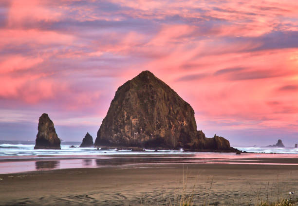 Haystack Rock in Cannon Beach at Dawn with watercolor sunrise stock photo