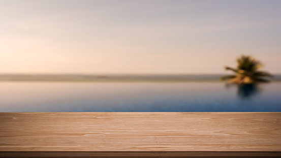 Empty wooden table with tropical infinity pool blurred abstract background