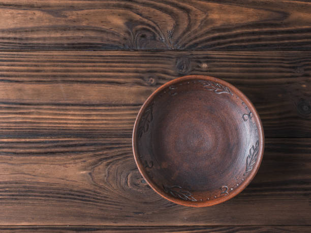 istock Clay bowl on a brown wooden table. Flat lay. 1157881235
