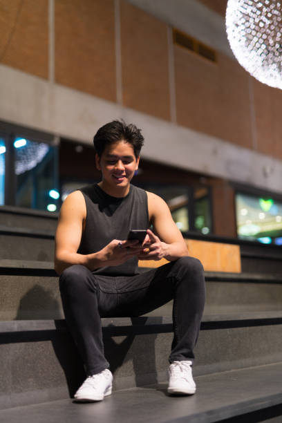istock Young happy handsome Asian man using phone in the city outdoors at night 1157881699