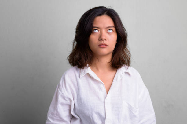 Portrait of young beautiful Asian woman with short hair Studio shot of young beautiful Asian woman with short hair against white background rolling eyes irritation displeased facial expression stock pictures, royalty-free photos & images