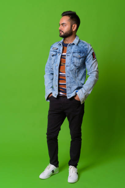 istock Young bearded Indian man against green background 1157889760