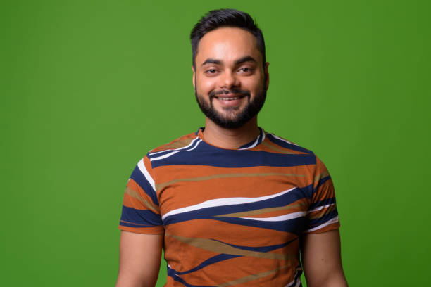 istock Young bearded Indian man against green background 1157889812