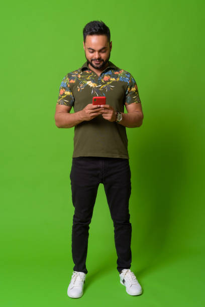istock Young bearded Indian man against green background 1157889857