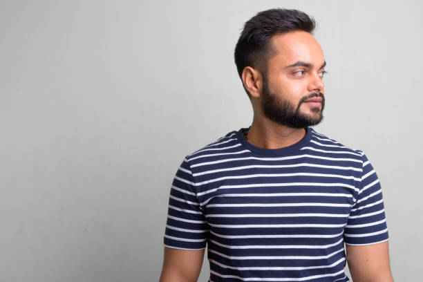 istock Young bearded Indian man against white background 1157889882