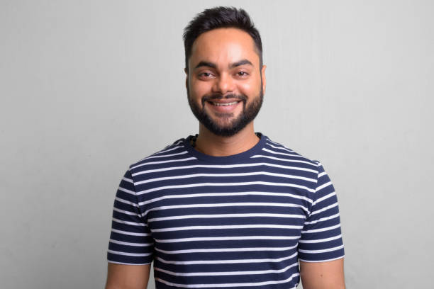 istock Young bearded Indian man against white background 1157889904