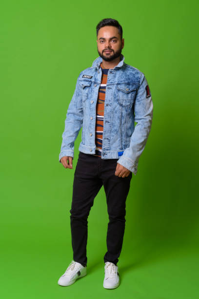 istock Young bearded Indian man against green background 1157889934
