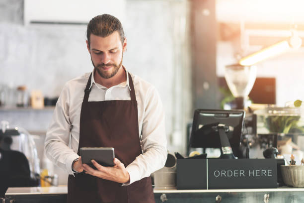 istock Male barista holding and looking at digital tablet. 1157896167