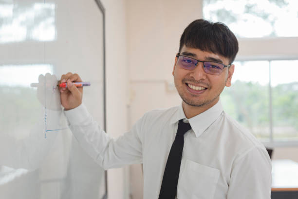 istock Young attractive man is writing a business plan on whiteboard 1157898356