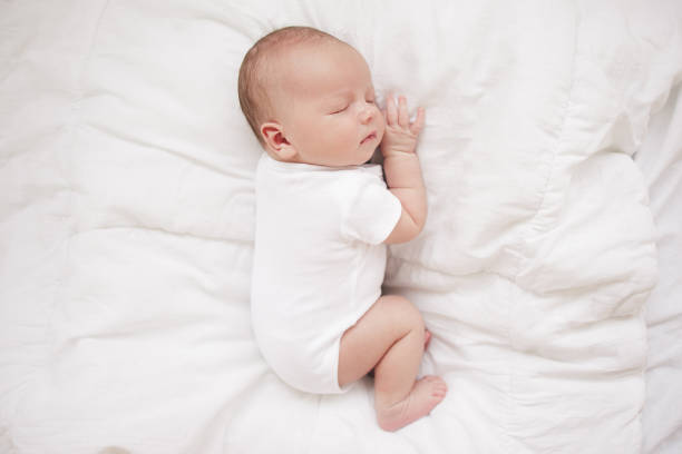istock little baby sleeping on a white bed 1157899236