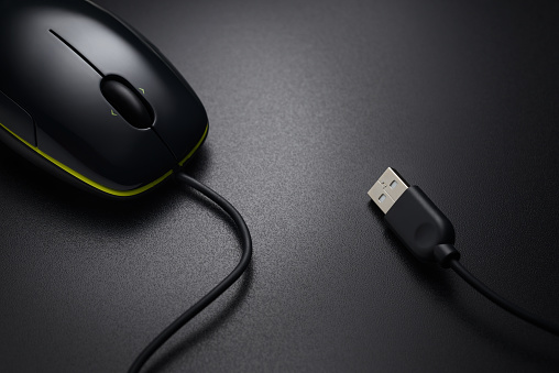 Black wired mouse on the dark office desk with copy space