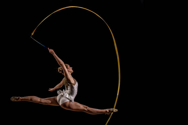 istock Gymnast doing rhythmic gymnastics with yellow ribbon 1157901645
