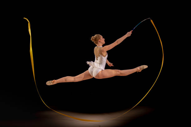 istock Gymnast doing rhythmic gymnastics with yellow ribbon 1157901663