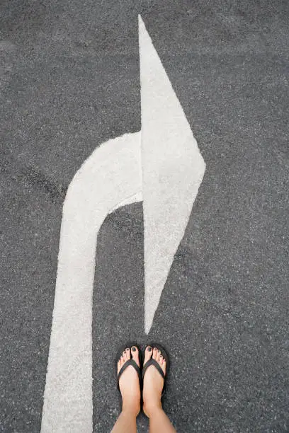 Turn Right Traffic Symbol. Feet and Arrows on Road Background. Woman Black Shoes or Sandals with Black Nail Polish Manicure Standing on the White Road Arrow. Chooses Forward Right Path Concept.