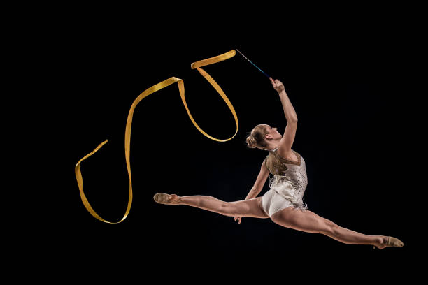 gymnast doing rhythmic gymnastics with yellow ribbon - the splits ethnic women exercising imagens e fotografias de stock