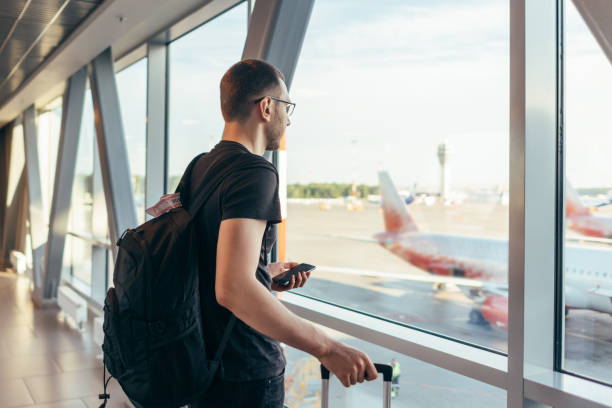 istock Man in airport near gate windows at planes on runway. 1157904219