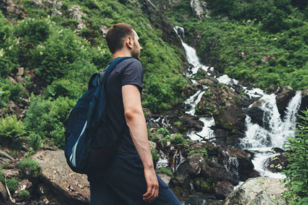 istock Young man looking at mountain stream in the forest admires nature. 1157904279