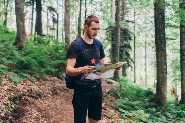 istock Hiker using a map to locate the destination in forest 1157904315