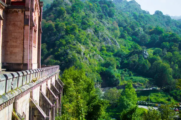 Photo of Side of Basilica of Covadonga in a hill, with the green forest at the background, in Cangas de Onis, Asturias, Spain