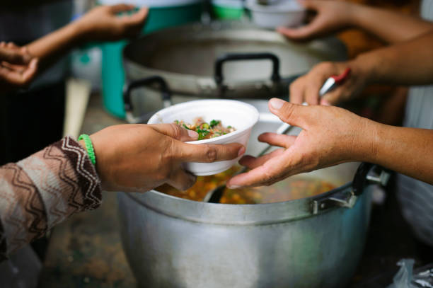 Hand offered to donate food from a rich man Share : The concept of social sharing : Poor people receiving food from donations : Homeless people are helped with food relief, famine relief : volunteers giving food to poor people in desperate need se ofrece a mano para donar alimentos de un hombre rico compartir : el concepto de compartir social : las personas pobres que reciben alimentos de donaciones : las personas sin hogar reciben ayuda con el alivio de alimentos, el alivio de la hambruna : volu