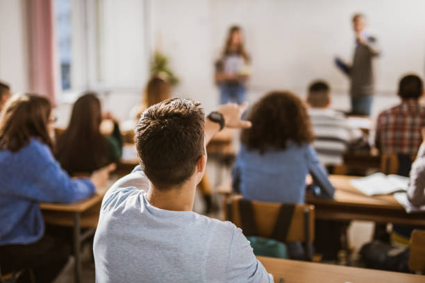 istock Back view of a male student talking to teacher on a class. 1157905480