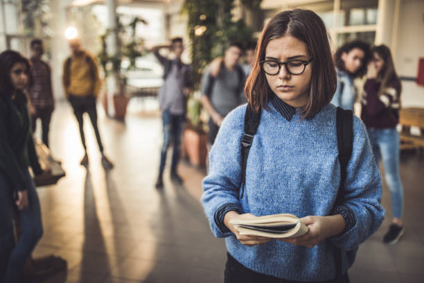istock Excluded high school student reading a book in a hallway. 1157908149
