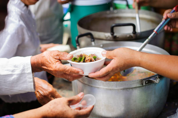 사회 가난한 사람들의 식량 필요 식량 기부 지원 : 노숙자가 사회의 음식 기증자로부터 자선 음식을 집어 들기 : 지구상의 거지 문제의 개념 - pauper 뉴스 사진 이미지