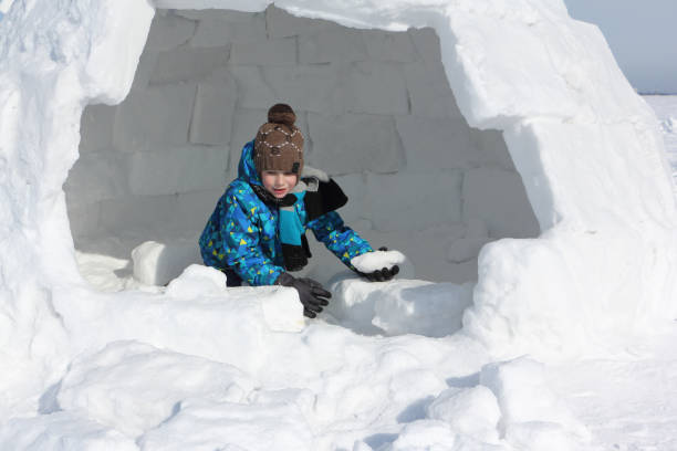 istock Happy cheerful boy building an igloo in winter 1157908316
