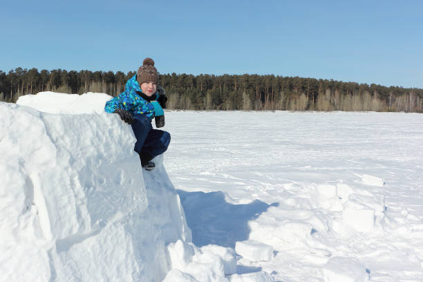 istock Happy boy sitting on an unfinished an igloo in winter 1157908321