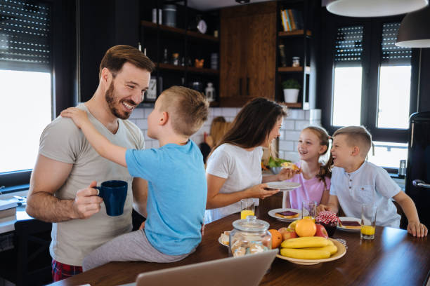 istock Father using laptop with son, family in background 1157910595