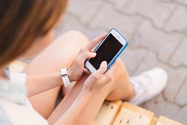 istock Pretty woman holding the phone in hands while touching the screen 1157912450