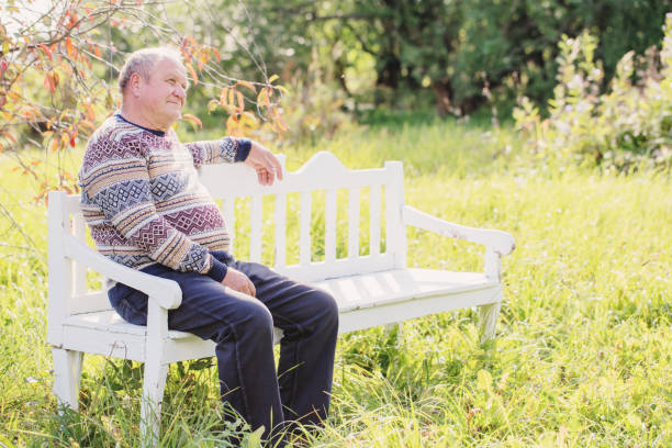 istock elderly man resting on white bench in autumn park 1157917025