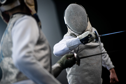 Fencer athletes fighting against black background during a Sporting Event.