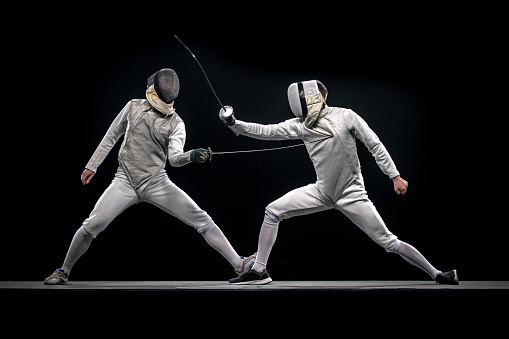 Fencer athletes fighting against black background during a Sporting Event.