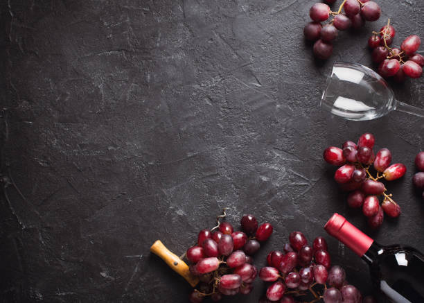 istock Wine red background with grapes, bottle and glasses, frame on black and dark texture 1157923823