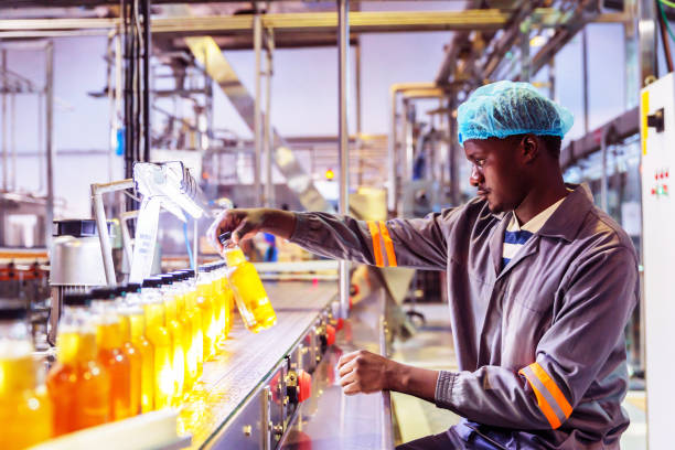 заводской рабочий проверяет бутылку на конвейерном поясе - bottling plant bottle filling production line стоковые фото и изображения