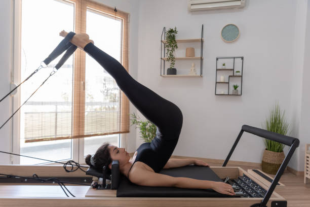 Jeune femme s'exerçant sur le lit de réformateur de pilates - Photo