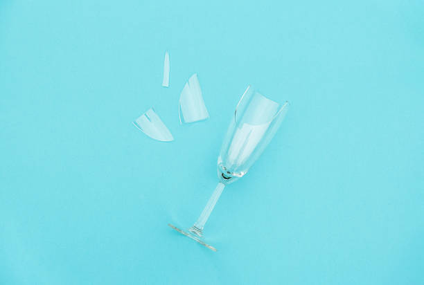 Broken champagne glass with splinters on blue background with copy space. Concept fight against alcoholism, drunkenness and refusal of alcohol. Creative Top view Flat lay stock photo