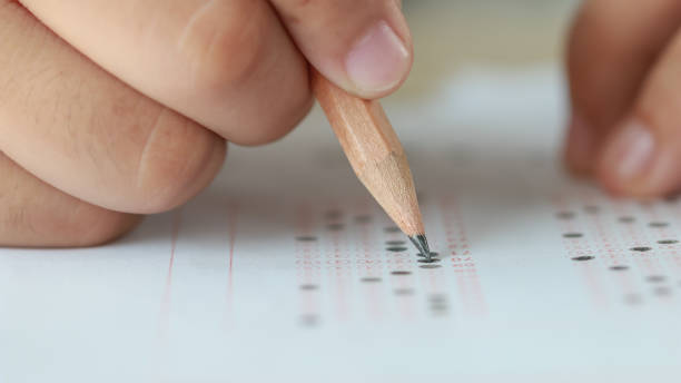 istock Education test in university or high school concept : Hands student holding pencil for testing exams on answer sheet, taking fill in exam document paper at campus classroom. Knowledge learning concept 1157932949